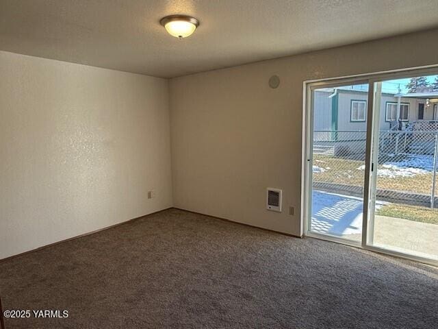 empty room featuring a textured ceiling, carpet, and a textured wall