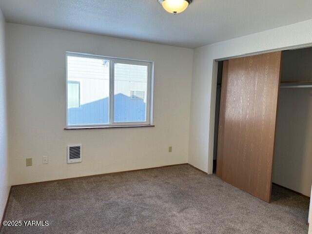 unfurnished bedroom featuring a closet, carpet, and visible vents