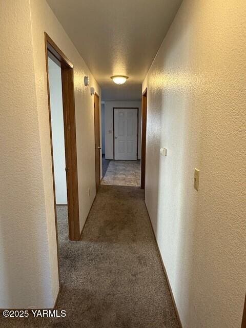 hall with carpet floors and a textured wall