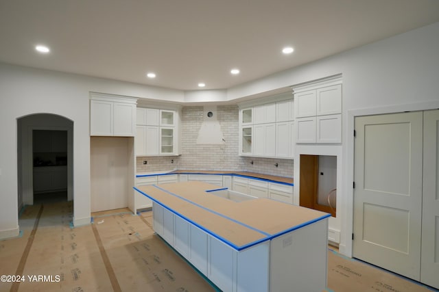 kitchen with tasteful backsplash, glass insert cabinets, a center island, white cabinetry, and recessed lighting