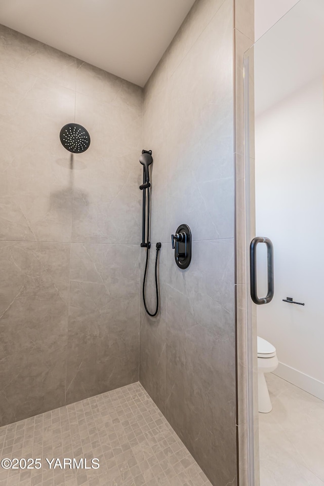 bathroom featuring a stall shower, baseboards, and toilet