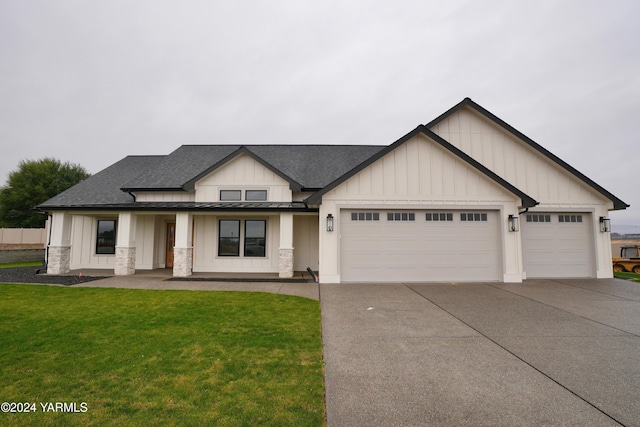 view of front facade featuring a garage, driveway, a shingled roof, a front lawn, and board and batten siding