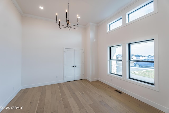 unfurnished dining area with baseboards, light wood-type flooring, visible vents, and crown molding