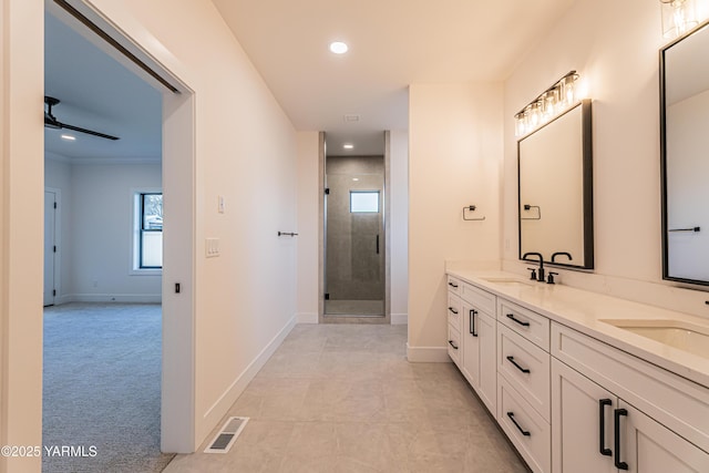 bathroom featuring double vanity, a stall shower, visible vents, and a sink