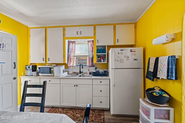 1311 W Mead Ave, Yakima, WA 98902 - kitchen featuring freestanding refrigerator, stainless steel microwave, a sink, light countertops, and dark wood-type flooring
