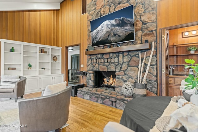 living area featuring a towering ceiling, wooden walls, a fireplace, and wood finished floors