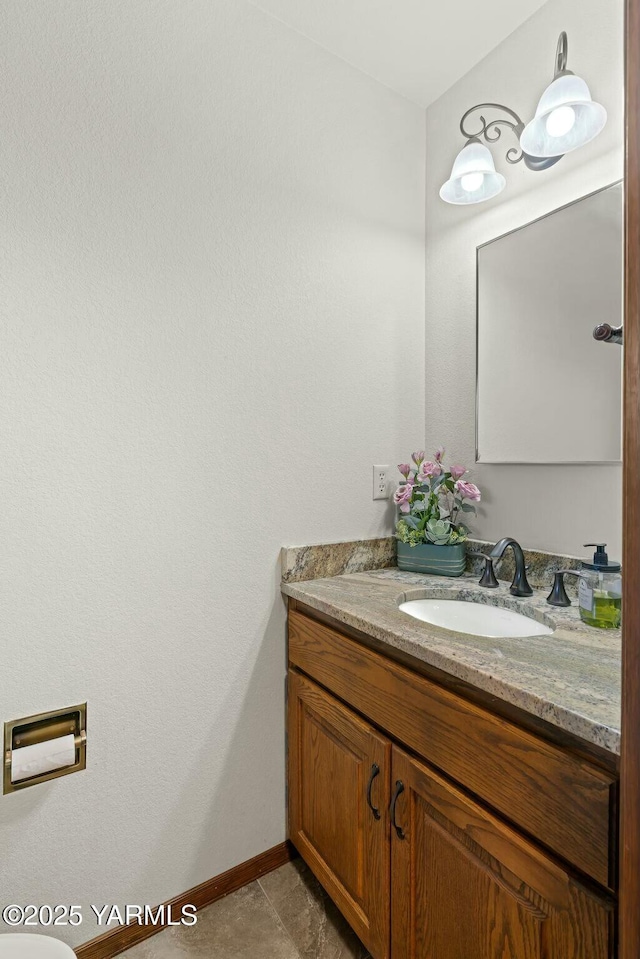 half bath with tile patterned flooring, baseboards, and vanity