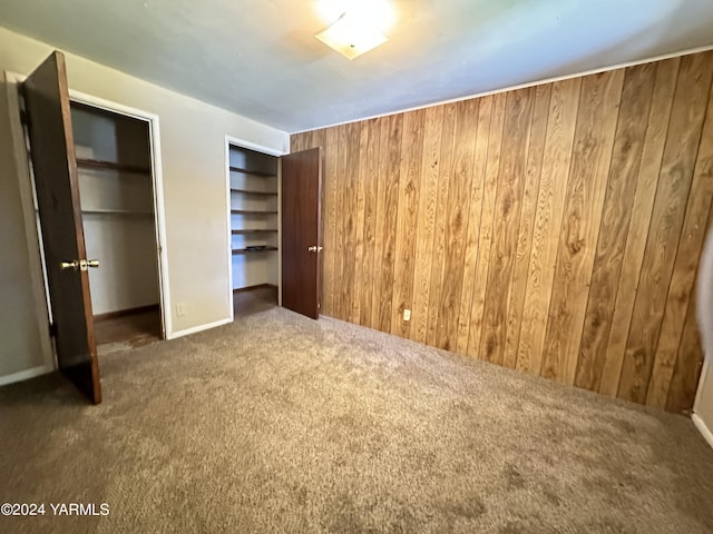 unfurnished bedroom with wood walls and dark carpet