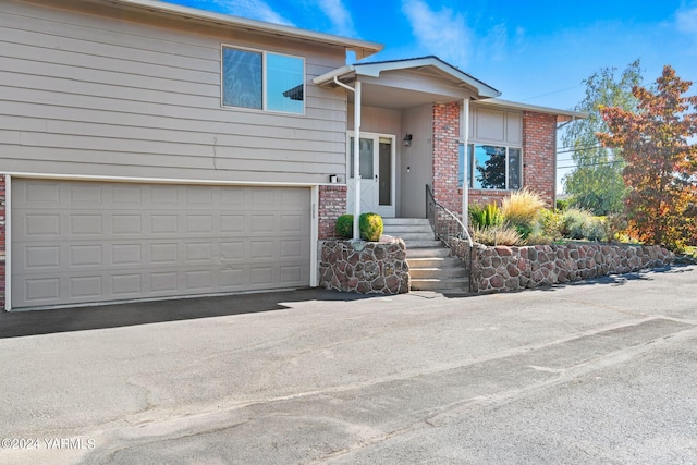 view of front of home featuring a garage, driveway, and brick siding