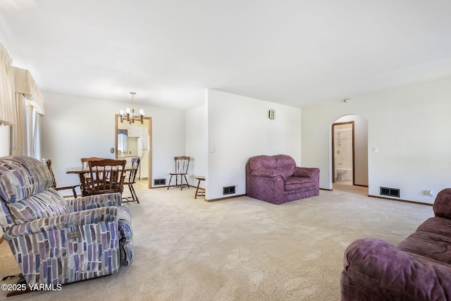 living room featuring carpet floors, visible vents, arched walkways, and a notable chandelier