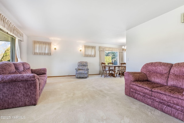 carpeted living area with baseboards and a chandelier