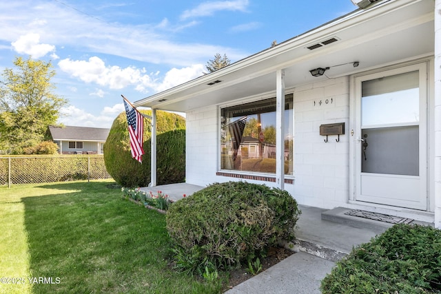 property entrance with fence, concrete block siding, a yard, and a porch