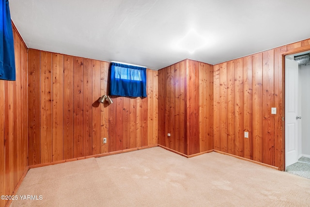 carpeted spare room with baseboards and wood walls