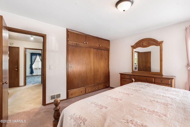 bedroom with visible vents, a closet, and light colored carpet