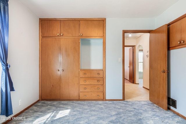 bedroom with visible vents, light carpet, arched walkways, a closet, and baseboards