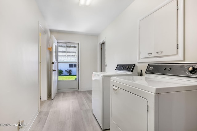 laundry area with washing machine and dryer, light wood-type flooring, and baseboards