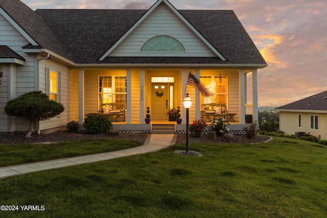 view of front facade featuring a porch, roof with shingles, and a front lawn