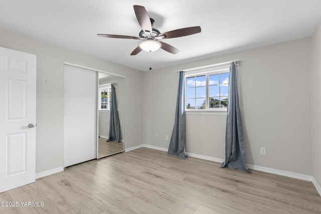 unfurnished bedroom with light wood-style floors, a closet, baseboards, and a ceiling fan