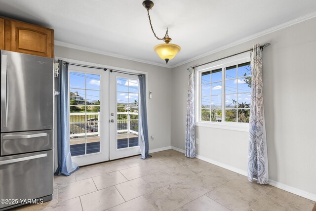 unfurnished dining area featuring french doors, plenty of natural light, crown molding, and baseboards