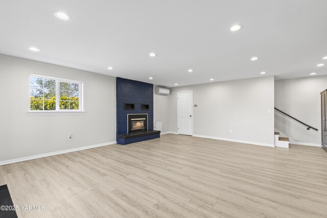 unfurnished living room with light wood-type flooring, recessed lighting, baseboards, and a large fireplace