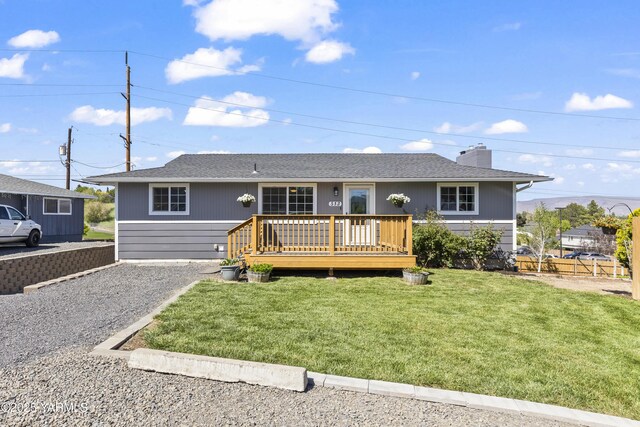 single story home featuring a wooden deck, a front yard, a chimney, and roof with shingles