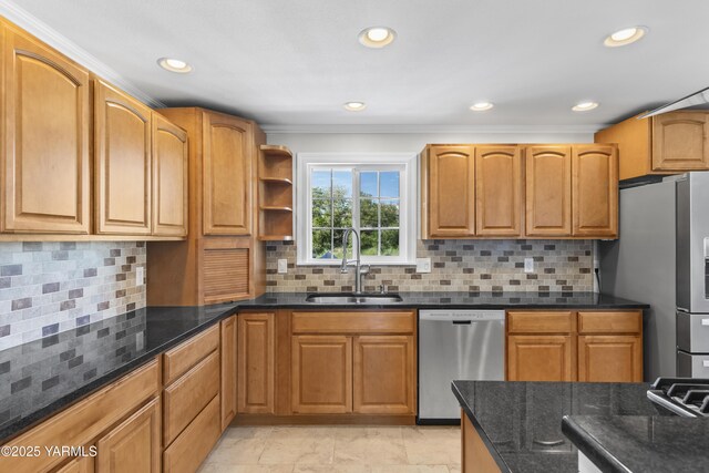 kitchen with stainless steel appliances, a sink, dark stone countertops, crown molding, and tasteful backsplash