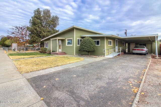 view of front facade with driveway, an attached carport, a front lawn, and fence