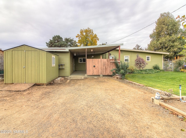 back of house with driveway, fence, an attached carport, and a yard