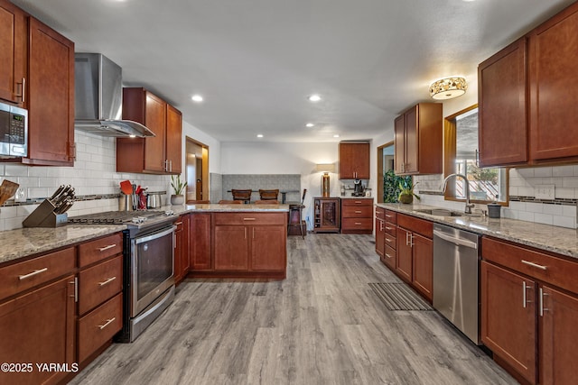 3603 Carol Ave, Yakima, WA 98902 - kitchen featuring wall chimney exhaust hood, appliances with stainless steel finishes, a sink, light wood-type flooring, and backsplash