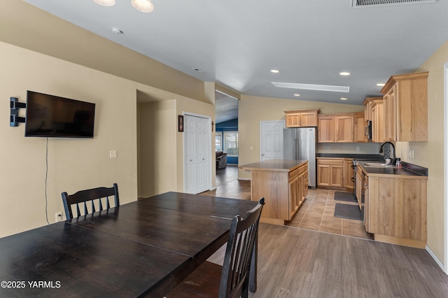 710 Columbus Ave, Moxee, WA 98936 - kitchen featuring freestanding refrigerator, a kitchen island, lofted ceiling, light wood finished floors, and light brown cabinetry