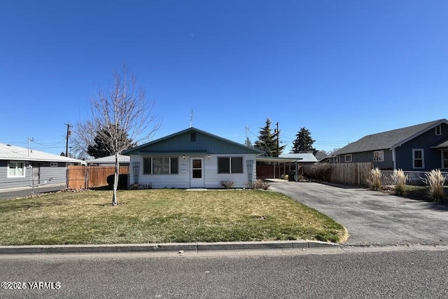 view of front facade featuring fence, aphalt driveway, a carport, and a front yard