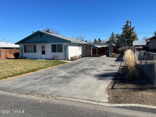 view of front facade with driveway, fence, a carport, and a front yard