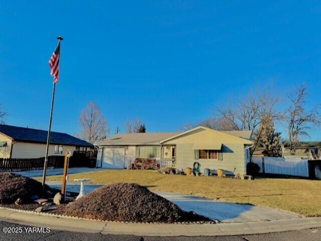 ranch-style home featuring an attached garage, fence, and a front lawn