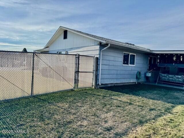 view of property exterior with a gate, fence, and a lawn