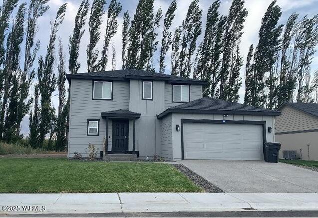 traditional-style home featuring an attached garage, central AC, a front yard, and concrete driveway