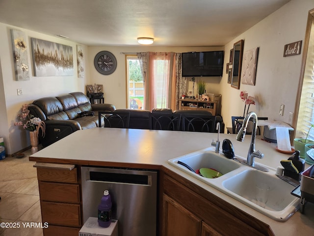 kitchen with a sink, stainless steel dishwasher, light countertops, open floor plan, and a peninsula