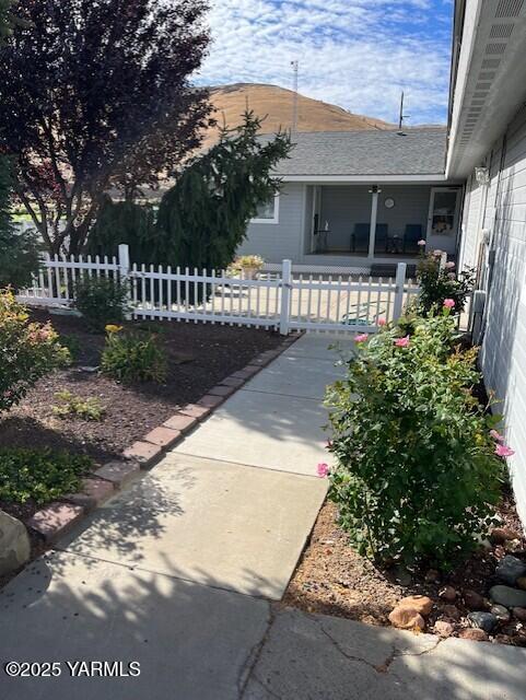 exterior space featuring a fenced front yard and a shingled roof