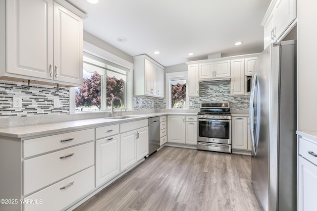 851 E Selah Rd, Yakima, WA 98901 - kitchen with stainless steel appliances, a sink, under cabinet range hood, light wood-type flooring, and white cabinets
