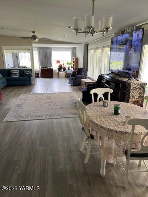 dining space featuring ceiling fan with notable chandelier and wood finished floors