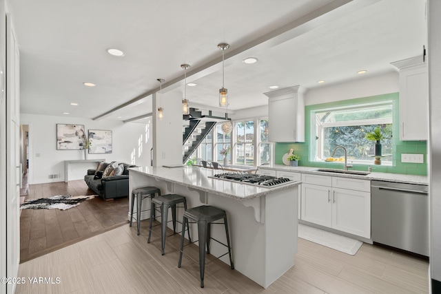 5 N 80th Ave, Yakima, WA 98908 - kitchen featuring light stone countertops, appliances with stainless steel finishes, a sink, open floor plan, and a breakfast bar area