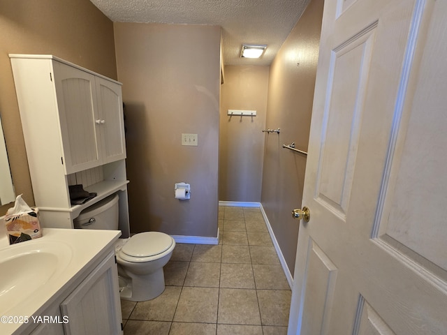 bathroom with tile patterned flooring, vanity, a textured ceiling, and toilet