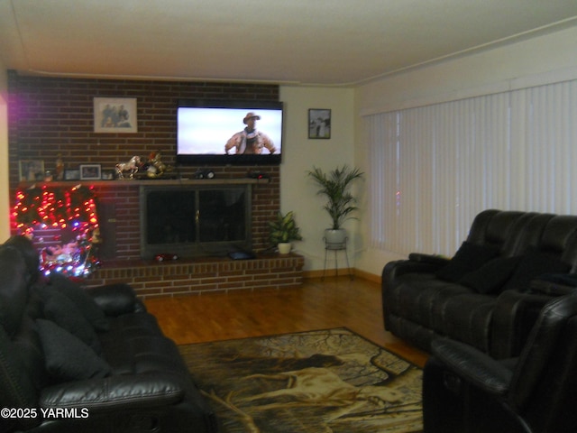 living room with a brick fireplace, baseboards, and wood finished floors