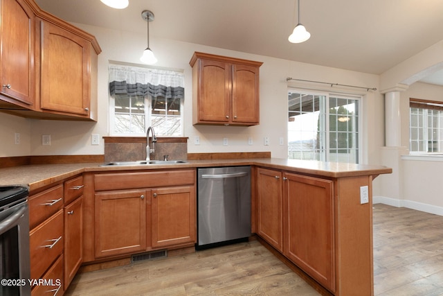 kitchen with visible vents, a peninsula, a sink, stainless steel appliances, and light wood-type flooring