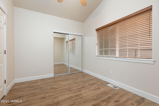 unfurnished bedroom with a closet, lofted ceiling, visible vents, and wood finished floors