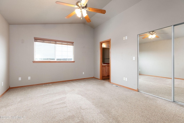 unfurnished bedroom with baseboards, visible vents, ensuite bath, vaulted ceiling, and carpet flooring