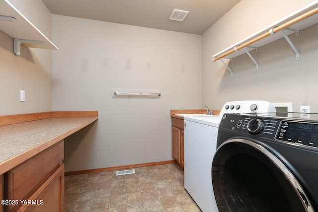 clothes washing area with independent washer and dryer, stone finish floor, baseboards, and visible vents