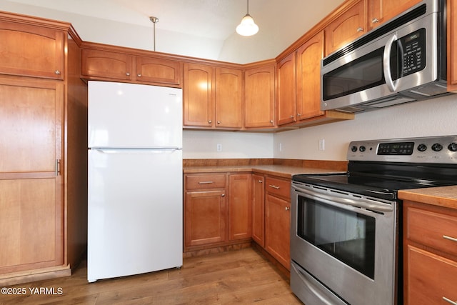 kitchen with hanging light fixtures, brown cabinets, stainless steel appliances, and light wood-style floors