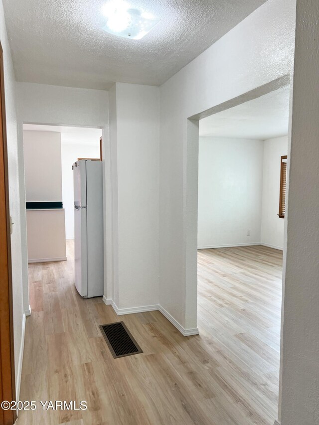 63 W Mead Ave, Yakima, WA 98902 - hallway featuring light wood finished floors, a textured ceiling, and baseboards