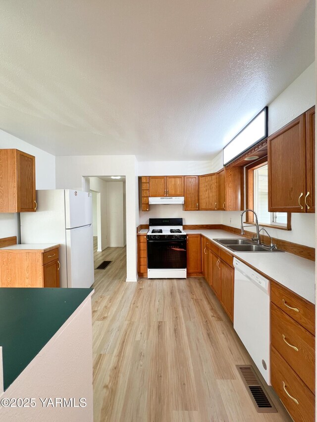 63 W Mead Ave, Yakima, WA 98902 - kitchen with white appliances, a sink, brown cabinets, light wood-style flooring, and light countertops