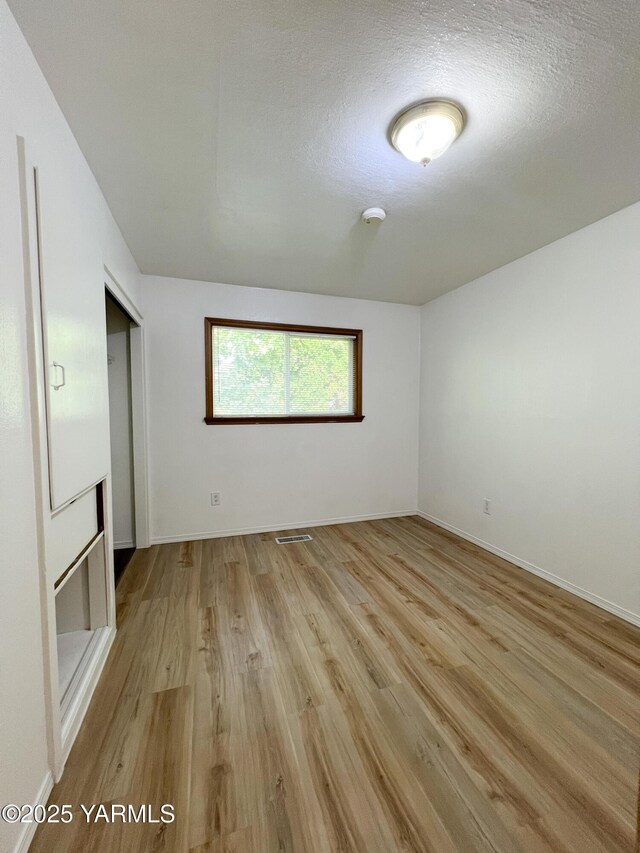 63 W Mead Ave, Yakima, WA 98902 - spare room featuring light wood-style floors, a textured ceiling, baseboards, and a smoke detector